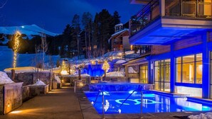 Un hotel con zona de piscina, paisajes nevados y montañas al fondo.