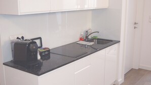 A modern kitchen with white cabinets, a black countertop, and a built-in coffee maker. - Apartment with terrace in a great city location 45 m2, only 2 minutes to subway (Wien)