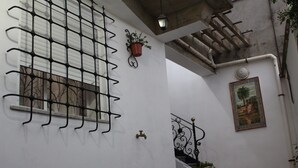 A narrow corridor with a white wall, a metal gate, a potted plant, a door with a brass handle, and a staircase with a railing. - Relaxing getaway, Studio between Béjaïa and JIJEL (Ziama Mansouriah)