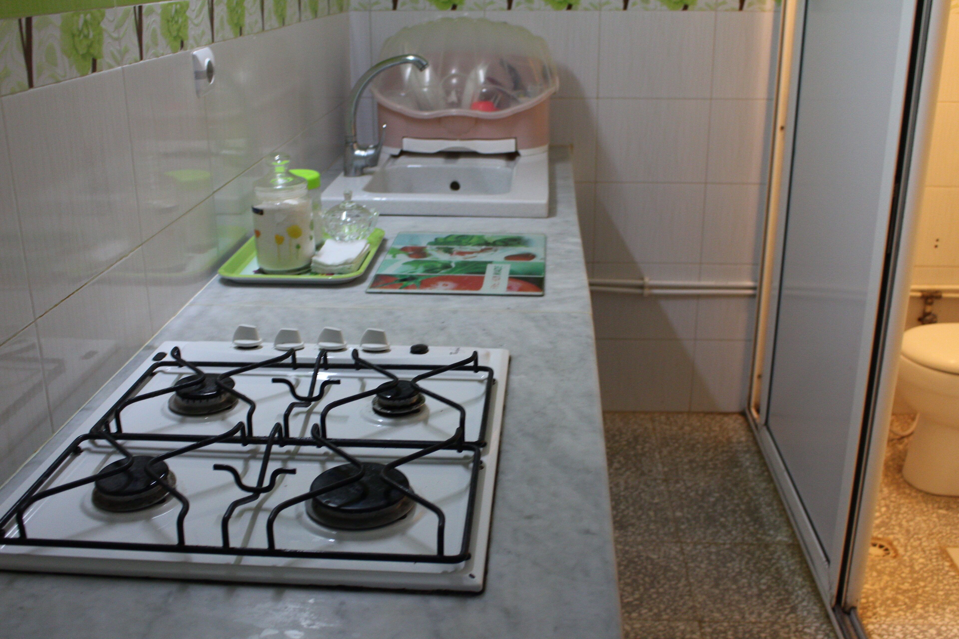 A kitchen with a gas stove, sink, and a small dish rack.