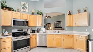 Una cocina moderna con armarios de madera, electrodomésticos de acero inoxidable y suelo de baldosas.
