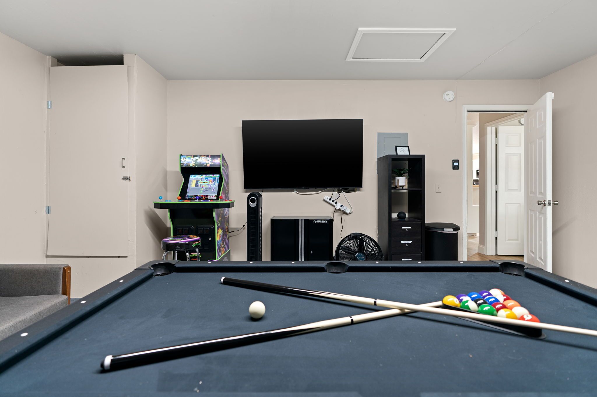 Ein Billardtisch mit Spielzeugstöcken und Kugeln, ein an der Wand befestigter Fernseher und eine kleine Spielhalle.