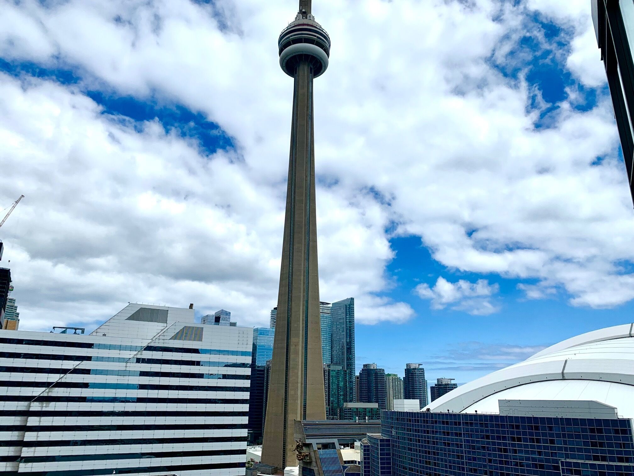A modern tower with a unique design, surrounded by contemporary buildings and a clear sky.