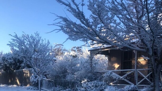 A snow-covered outdoor area with a wooden fence, a small building with a porch, and a pathway. - Larsen's Cottage #2: Historic 1880 Home (Mount Victoria)