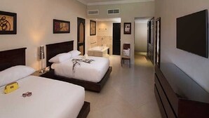 Ein Hotelzimmer mit zwei Betten, einem Badezimmer und einem Fernseher.