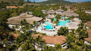 Ein Resort mit mehreren Hütten mit traditionellen Strohdächern, einem zentralen Schwimmbecken und üppiger Vegetation.