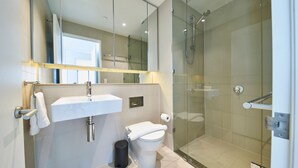 Een moderne badkamer met een douchecabine van glas, een wit wastafelmeubel en een toilet.
