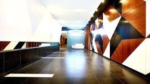 Un hall d’hôtel moderne avec un long comptoir d’accueil, un espace salon et un mur orné d’un motif géométrique.