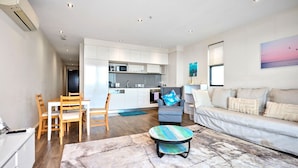 Un salon moderne comprenant un canapé, une table basse et un coin repas avec des chaises.