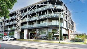 Un edificio moderno de varios pisos con una fachada geométrica distintiva, grandes ventanales y una cafetería en la planta baja.
