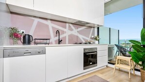 Una cocina moderna con lavavajillas, horno y vistas a la ciudad a través de amplios ventanales.