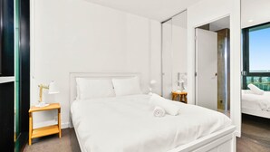 A modern hotel room with a large bed, a bedside table with a lamp, and a wardrobe. - Mr Clarke - Prime Cityscape with Parking (Southbank)