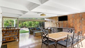 An open-plan living area with a dining table, chairs, a sofa, and a wooden cabinet.