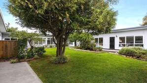 A modern house with a well-maintained lawn, a large tree in the front yard, and a white exterior. - Rosebud Beachfront Haven  Coastal Bliss Four (Capel Sound)