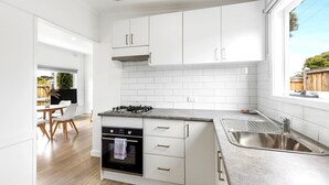 A modern kitchen with white cabinets, a gas stove, and a stainless steel sink. - Rosebud Beachfront Haven  Coastal Bliss Five (Capel Sound)