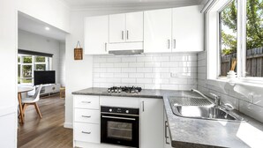 A modern kitchen with white cabinets, a gas stove, an oven, and a sink.