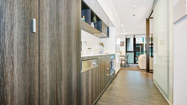 Una cucina moderna con mobili in legno, forno integrato e un piano di lavoro con diversi oggetti.