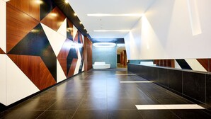 Hall d'hotel moderna con pareti a motivi geometrici, una reception e una zona relax.