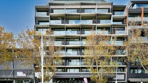 Un edificio a più piani con balconi, un negozio e un cartello che indica la disponibilità per affitto.