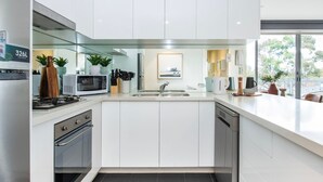 A modern kitchen with white cabinetry, a stainless steel range, a microwave, and a dishwasher.