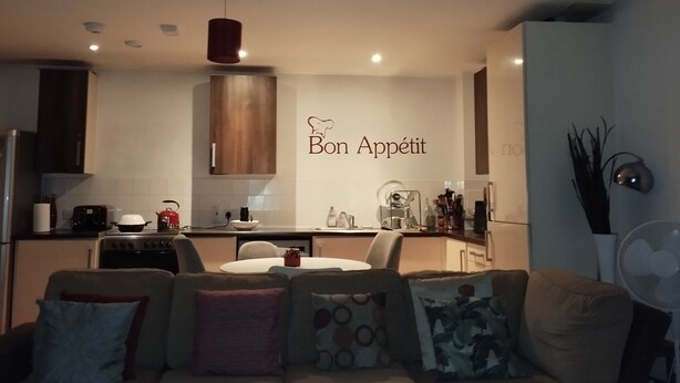 Eine moderne Küche mit Essbereich, einer Couch und einer Wand mit dem Schriftzug 'Bon Appétit'.