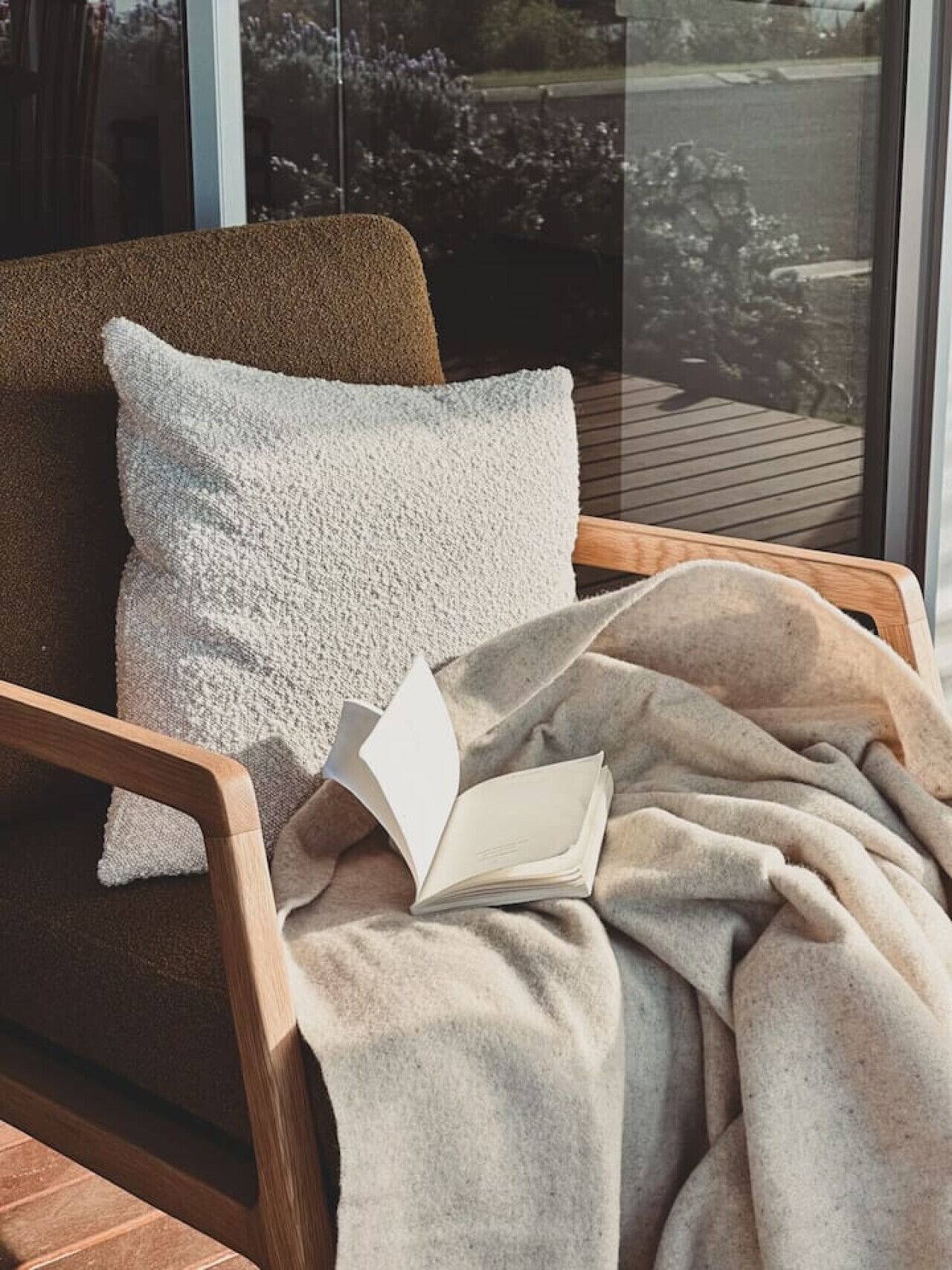 Un coin lecture confortable avec un fauteuil, une couverture et un livre ouvert.