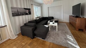 A modern living room with a sectional sofa, a TV, and a chandelier.