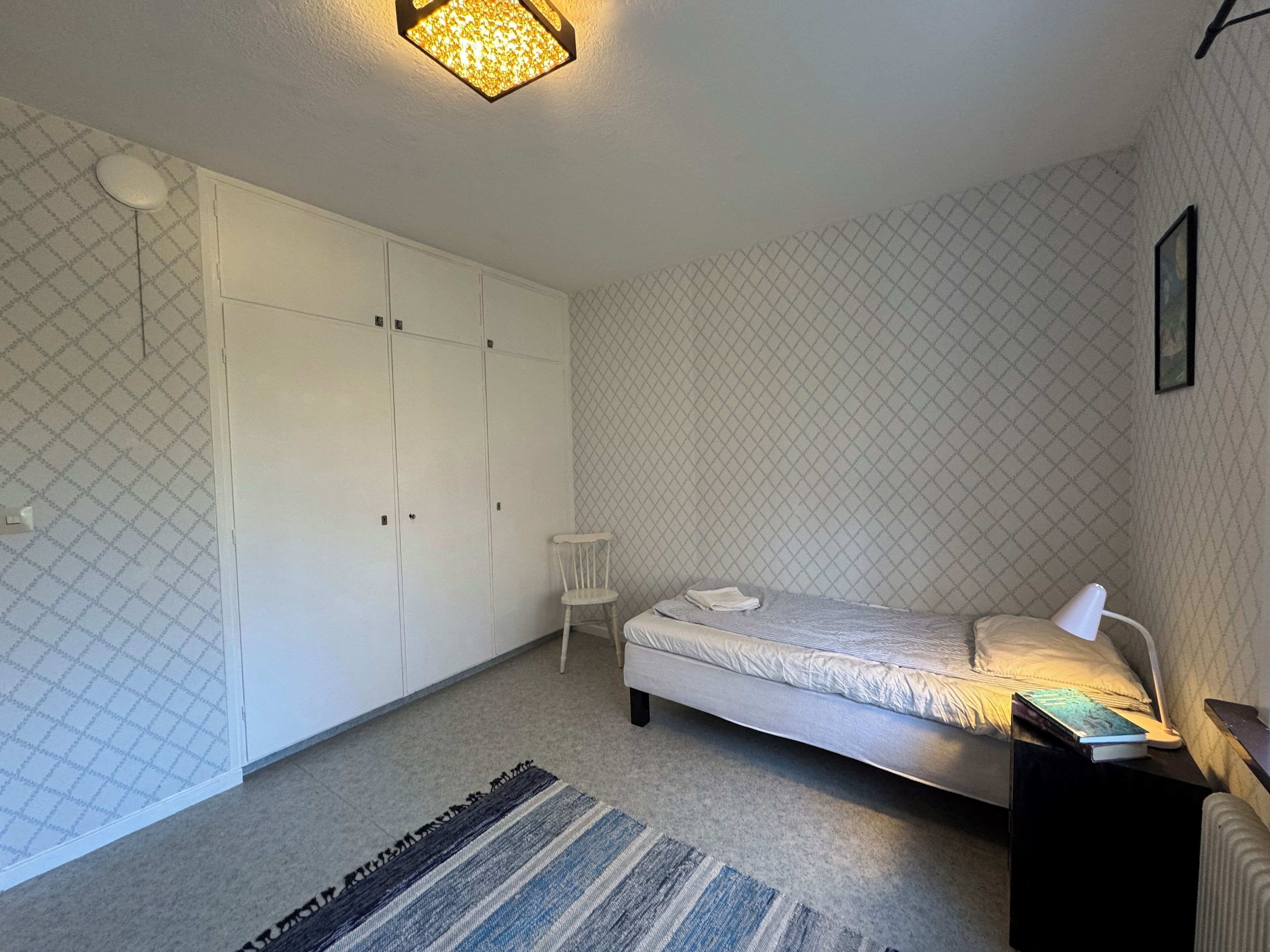 Une chambre à coucher comprenant un lit, une chaise, une table de chevet et une armoire.