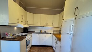 A compact kitchen with white cabinets, a stove, an oven, and a refrigerator.