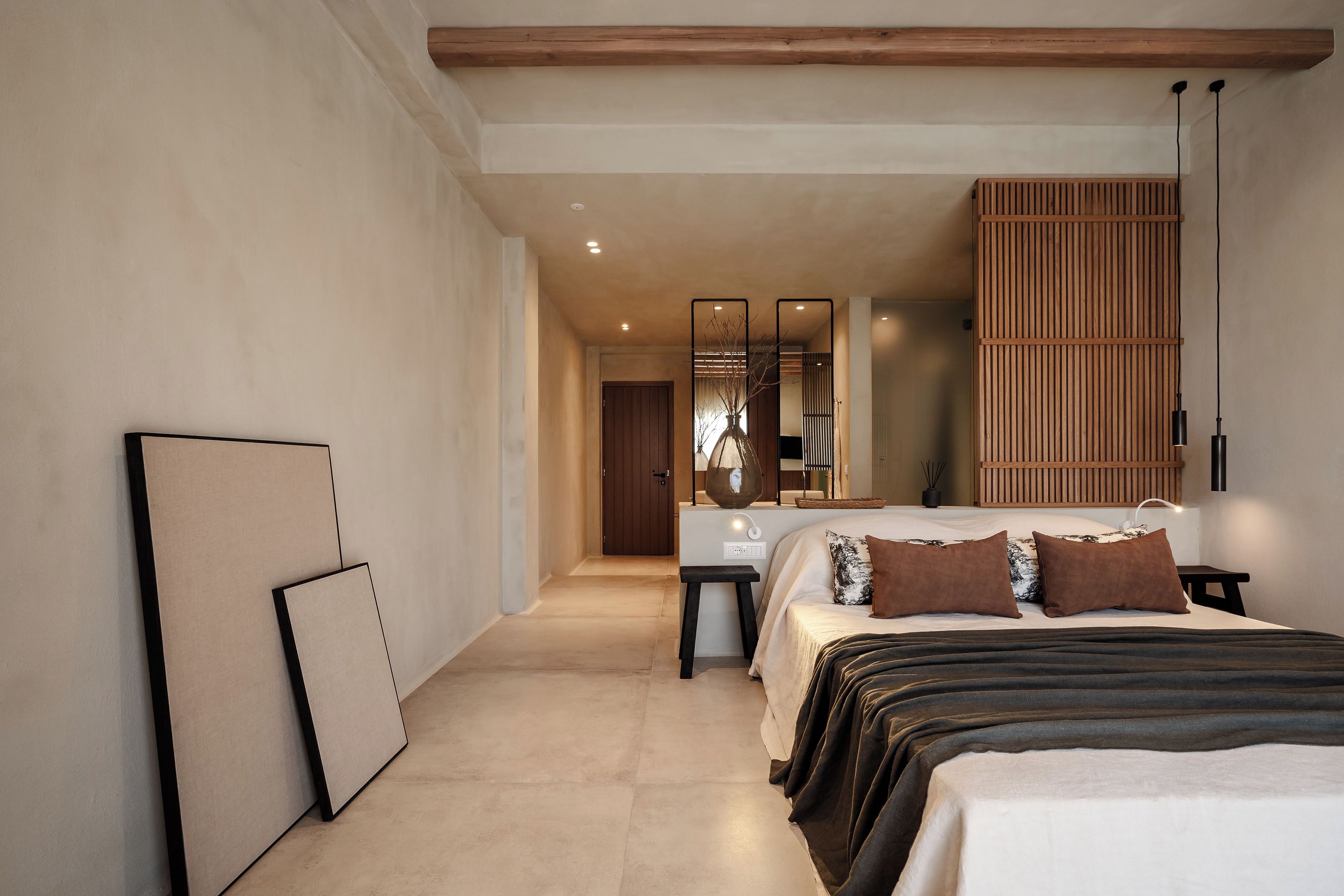 Un dormitorio moderno con una cama grande, mesitas de noche, un espejo y un panel de pared de madera.