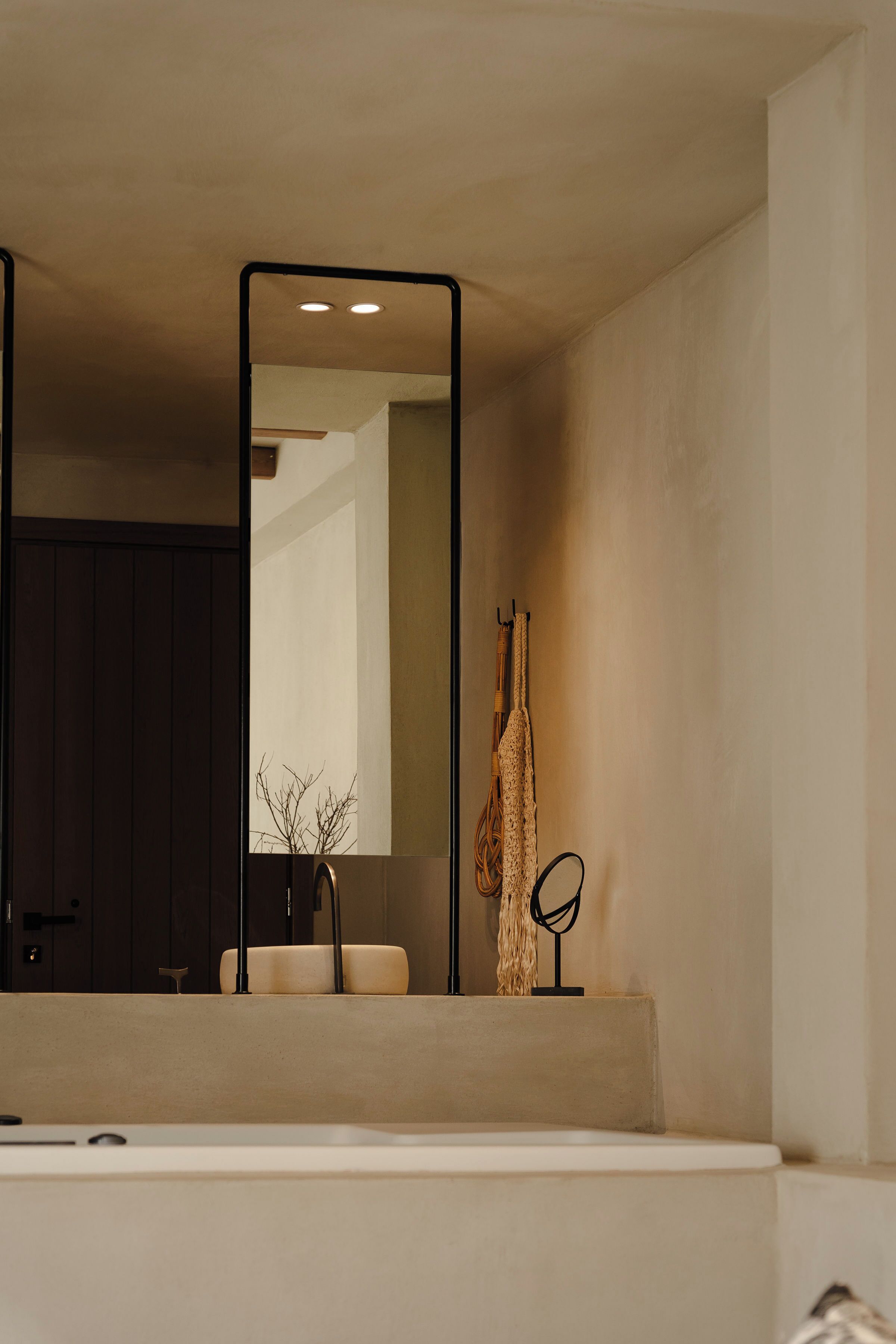 Un baño con un espejo grande, un perchero y un lavabo.