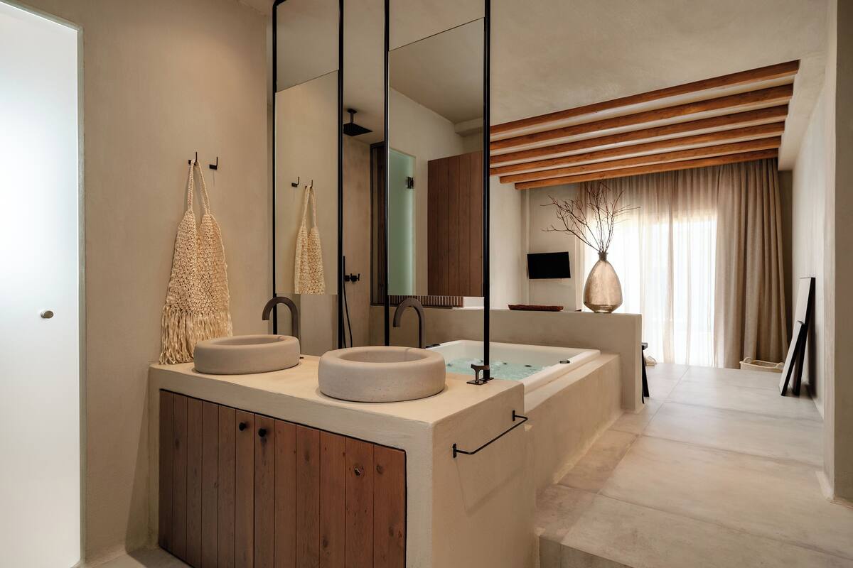 A modern bathroom with two sinks, wooden cabinets, a large mirror, and a bathtub.