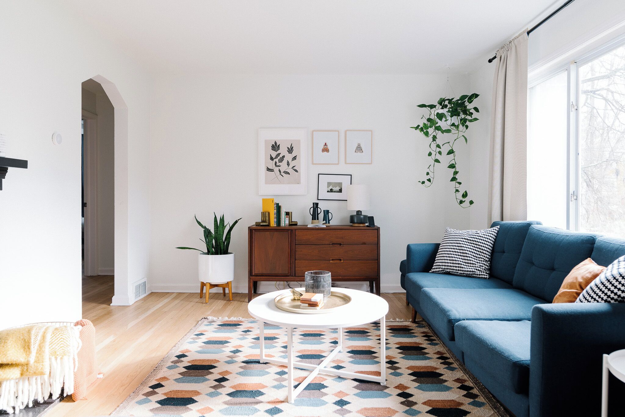 A modern living room with a blue sofa, a white coffee table, and a patterned rug.