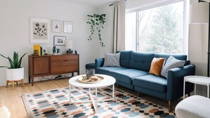 A modern living room with a blue sofa, a white coffee table, and a patterned rug. - Cuyahoga Valley National Park, Hiking,Dog Friendly (Brecksville)