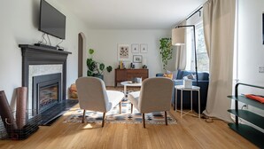 A modern living room with a fireplace, a flat-screen TV mounted above it, a sofa, a coffee table, and a side table. - Cuyahoga Valley National Park, Hiking,Dog Friendly (Brecksville)