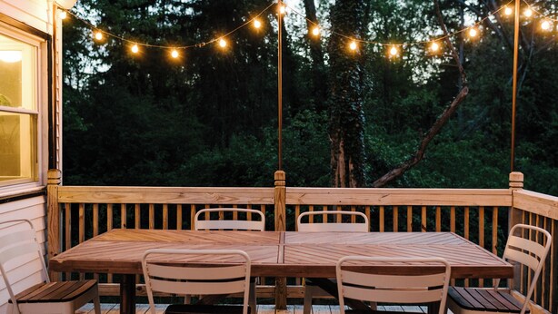 A wooden deck with a table and chairs, surrounded by string lights and trees. - Cuyahoga Valley National Park, Hiking,Dog Friendly (Brecksville)