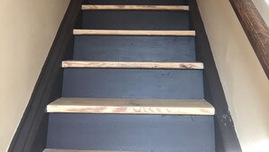 A staircase with dark steps and a wooden handrail, leading to a door at the top.