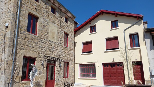A two-story building with stone walls and red-framed windows.