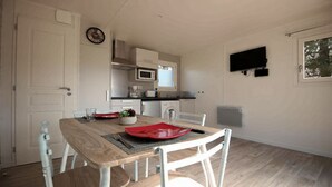 Cocina pequeña con armarios blancos, microondas y televisor montado en la pared.