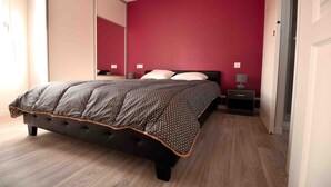 Un dormitorio con una cama grande, una mesita de noche, una lámpara y un espejo.