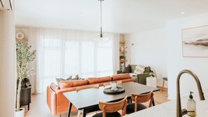 A modern kitchen with a dining area, featuring a large table, chairs, and a built-in oven. - The Kings Domain - Luxurious townhouse in the CBD (Blenheim)