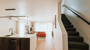 A modern kitchen with a dishwasher, a dining area with a sofa, and a staircase. - The Kings Domain - Luxurious townhouse in the CBD (Blenheim)