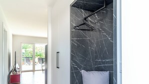 Un intérieur moderne avec un mur en marbre noir, un plancher en bois et une vue sur un espace extérieur.