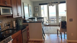 A kitchen with wooden cabinets, a microwave, and a dining area with a view of the beach.