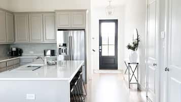 A modern kitchen with a large island, stainless steel appliances, and light wood flooring.