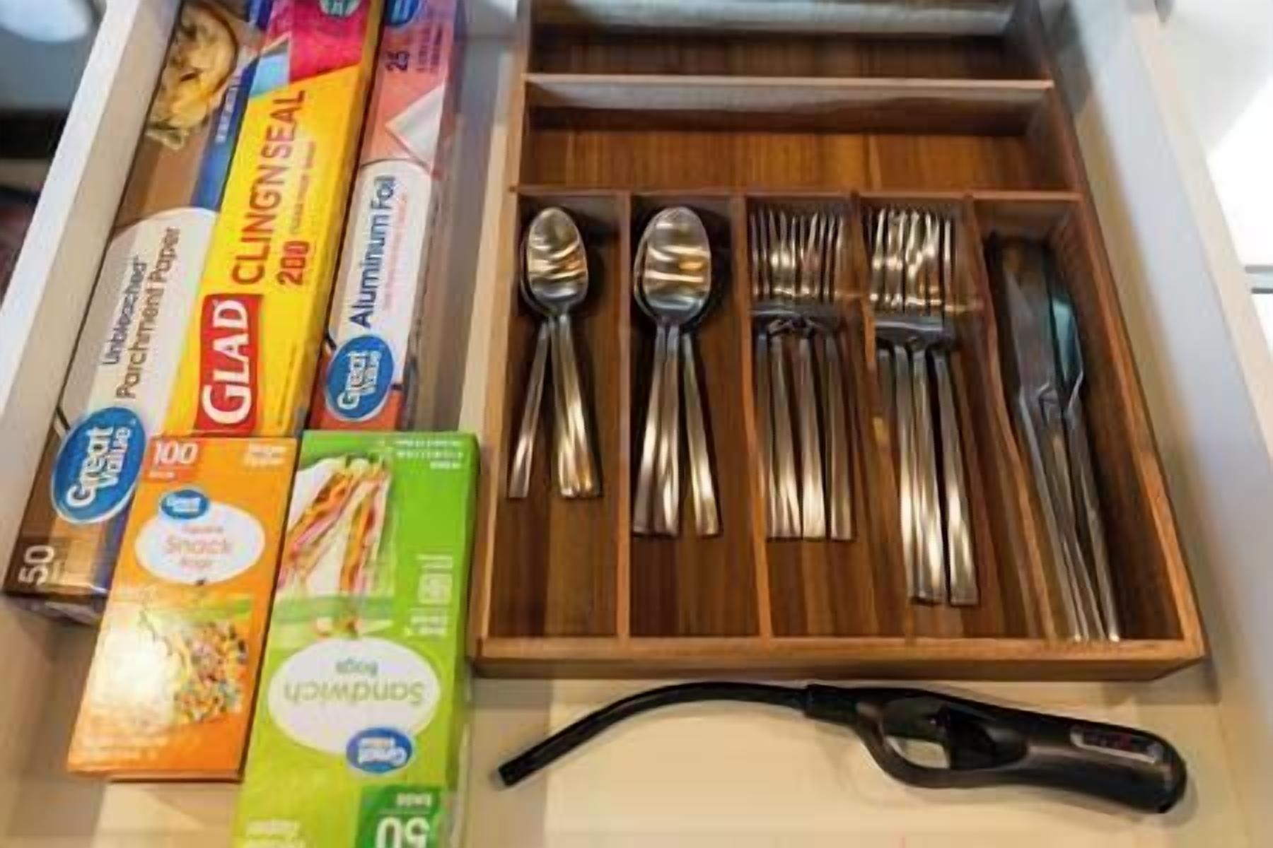 A drawer containing various kitchen utensils and packaged food items.