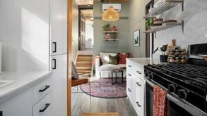 Una cocina moderna con armarios blancos, techo de madera y una lámpara colgante.
