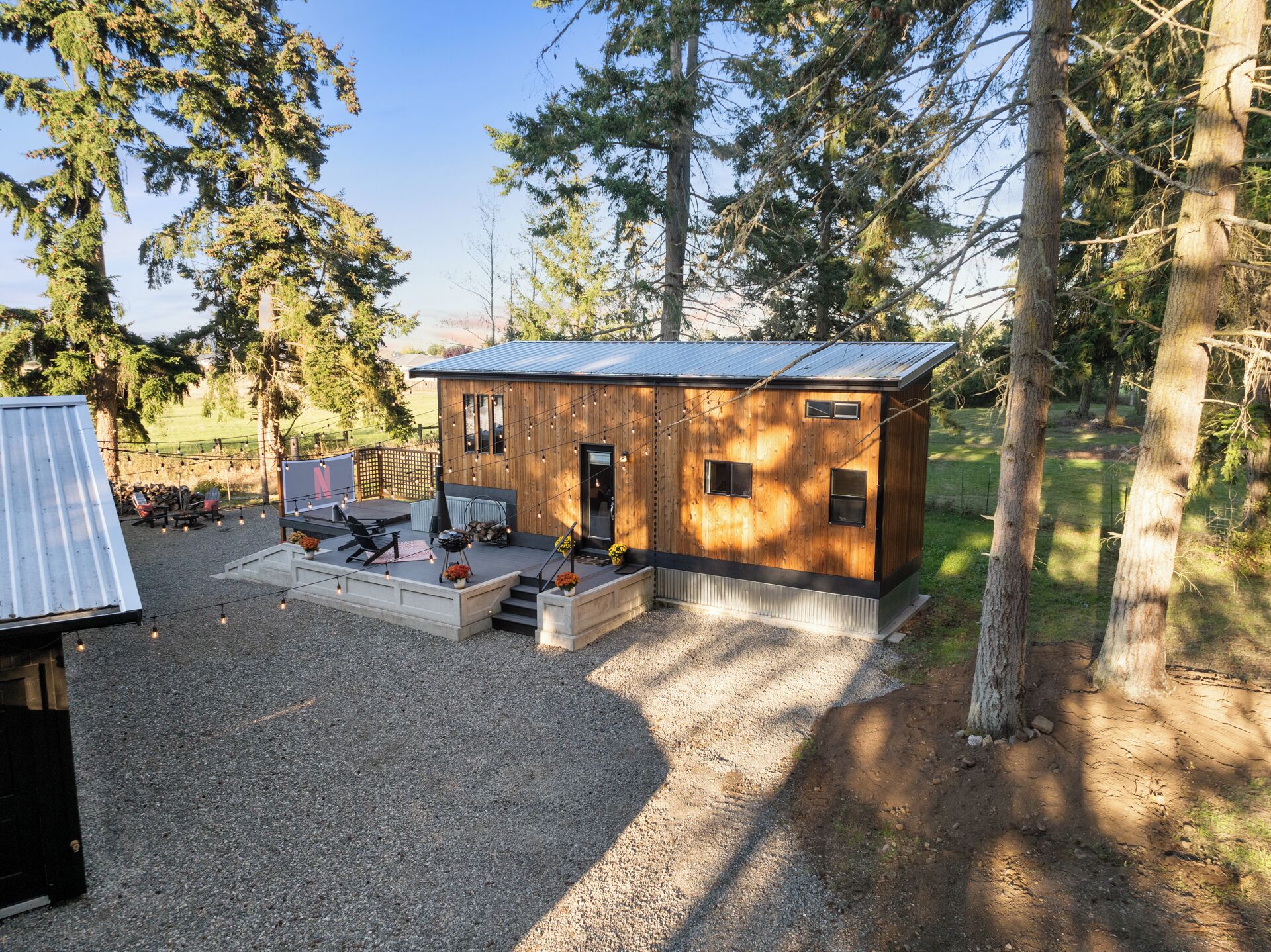 Une cabane rustique avec une façade en bois, un toit en métal et une allée gravillonnée.