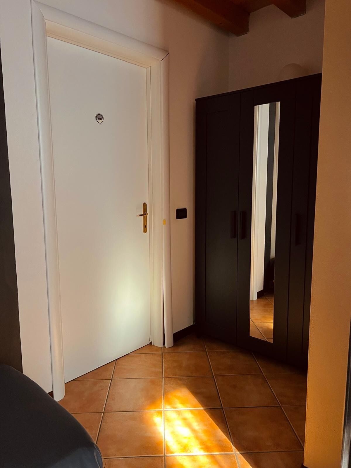 Ein Flur mit einer weißen Tür, einem dunklen Wandschrank und einem gefliesten Boden.