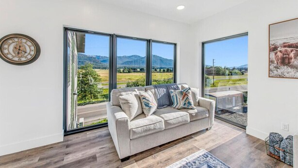 A spacious living room with a large window offering a scenic view of a valley and mountains. - High-end, convenient, new build! (Juneau)